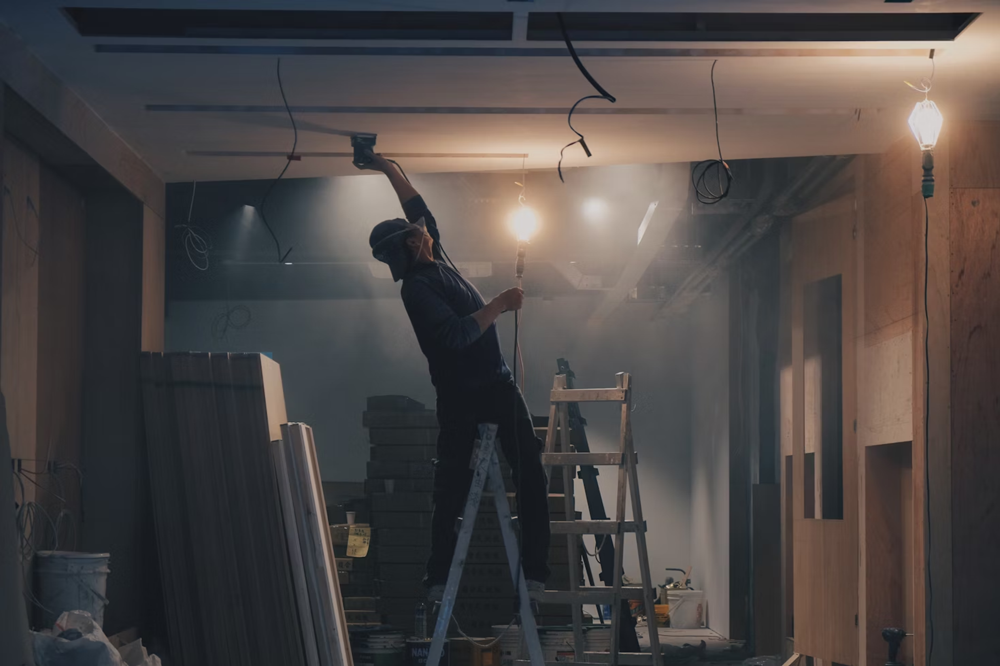 Image of a man fixing the ceiling on a ladder.